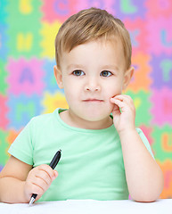 Image showing Little boy is writing on his copybook