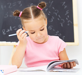 Image showing Little girl is writing using a pen