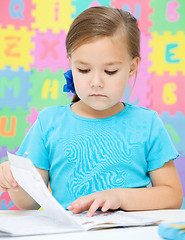 Image showing Little girl is writing using a pen