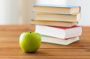 Image showing close up of books and green apple on wooden table