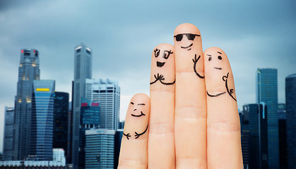 Image showing close up of fingers with smiley faces over city