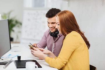 Image showing smiling creative team with smartphones at office