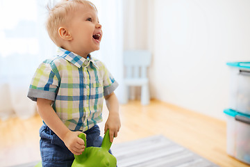 Image showing happy baby boy playing with ride-on toy at home