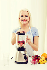 Image showing smiling woman with blender preparing shake at home