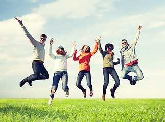 Image showing smiling friends in sunglasses jumping high