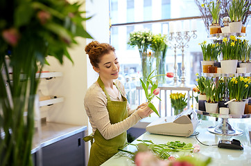 Image showing smiling florist woman making bunch at flower shop