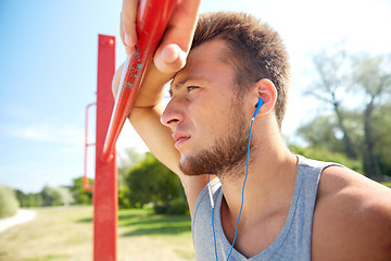 Image showing young man with earphones and horizontal bar