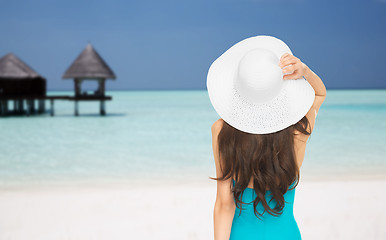 Image showing woman in swimsuit and sun hat from back on beach