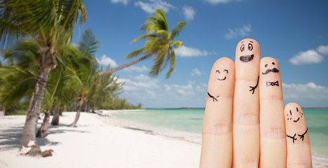 Image showing close up of fingers with smiley faces on beach