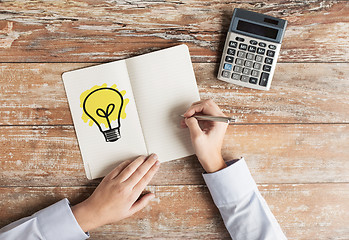 Image showing close up of hands with calculator and notebook