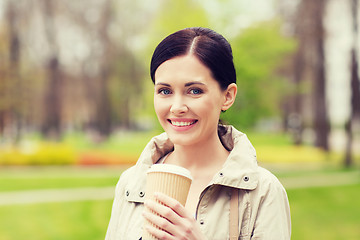 Image showing smiling woman drinking coffee in park