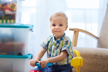 Image showing happy little baby boy driving ride-on car at home