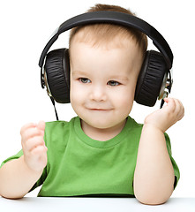 Image showing Cute little boy enjoying music using headphones