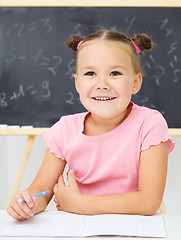 Image showing Little girl is writing using a pen