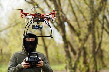 Image showing Man in mask operating a drone with remote control.