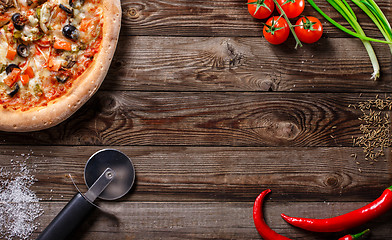 Image showing Tasty pizza with ingridients on a wooden board.