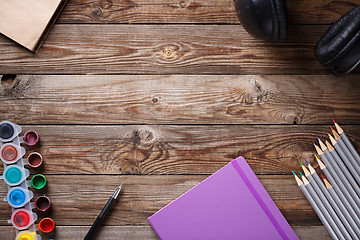 Image showing Watercolors, color pencils and sketchbook on wooden table. Flat lay photo with empty space for logo, text.