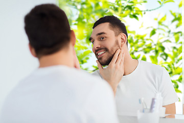 Image showing happy young man looking to mirror at home bathroom