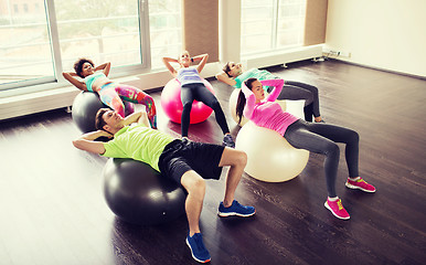 Image showing happy people flexing abdominal muscles on fitball