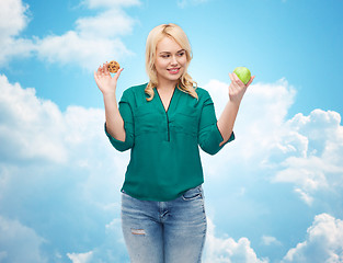 Image showing smiling woman choosing between apple and cookie