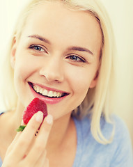 Image showing happy woman eating strawberry at home