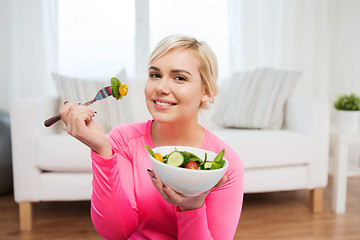 Image showing smiling young woman eating salad at home