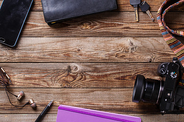 Image showing Travel concept - headphones, camera,  sketchbook, purse, pencil and keys on wooden background.