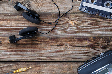 Image showing Cassette tapes, cassette player and headphones over wooden table. top view.