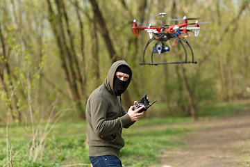 Image showing Man in mask operating a drone with remote control.