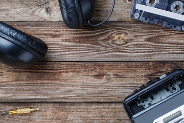 Image showing Cassette tapes, cassette player and headphones over wooden table. top view.