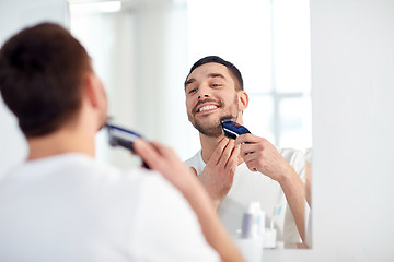 Image showing man shaving beard with trimmer at bathroom