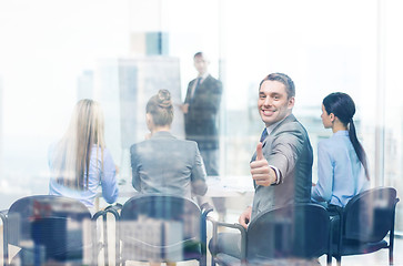 Image showing businessman with team showing thumbs up in office