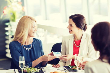 Image showing happy women giving birthday present at restaurant