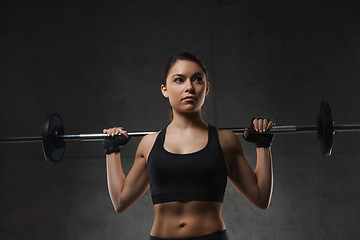 Image showing young woman flexing muscles with barbell in gym