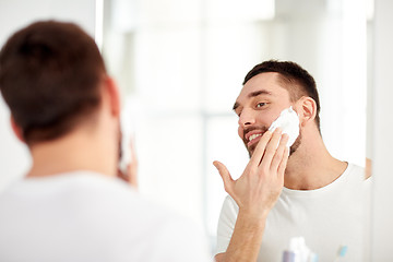 Image showing happy man applying shaving foam at bathroom mirror