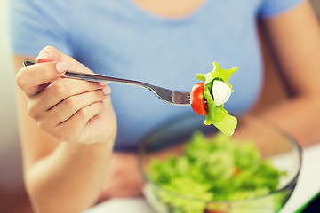 Image showing close up of young woman eating salad at home