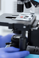 Image showing close up of hands with microscope and blood sample