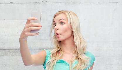 Image showing funny young woman taking selfie with smartphone