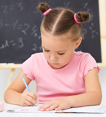 Image showing Little girl is writing using a pen