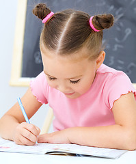 Image showing Little girl is writing using a pen