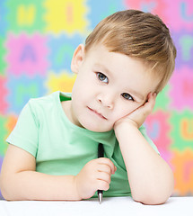 Image showing Little boy is writing on his copybook