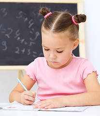 Image showing Little girl is writing using a pen