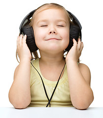 Image showing Little girl is enjoying music using headphones