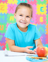 Image showing Little girl is writing using a pen