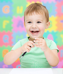 Image showing Little girl is writing using a pen