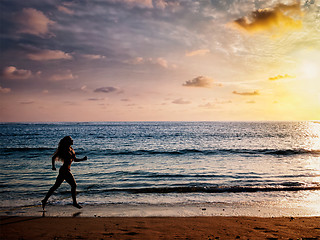 Image showing Beautiful athletic woman running along sea beach in the morning