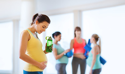 Image showing happy pregnant woman with water bottle in gym