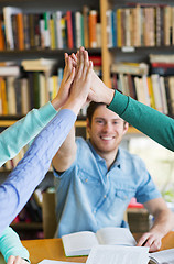 Image showing students with books making high five in library