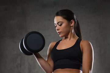 Image showing young woman flexing muscles with dumbbells in gym