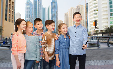 Image showing happy children with smartphone and selfie stick